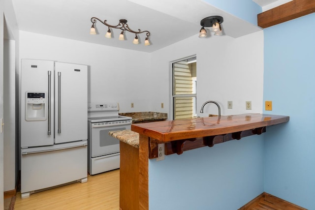 kitchen with white appliances, light hardwood / wood-style flooring, and kitchen peninsula