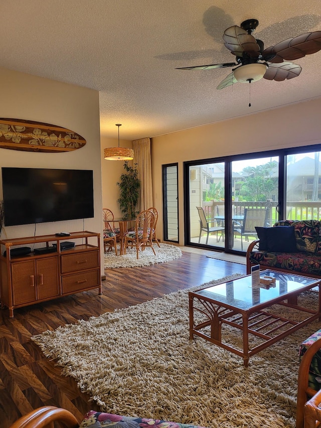 living room with ceiling fan, dark hardwood / wood-style floors, and a textured ceiling