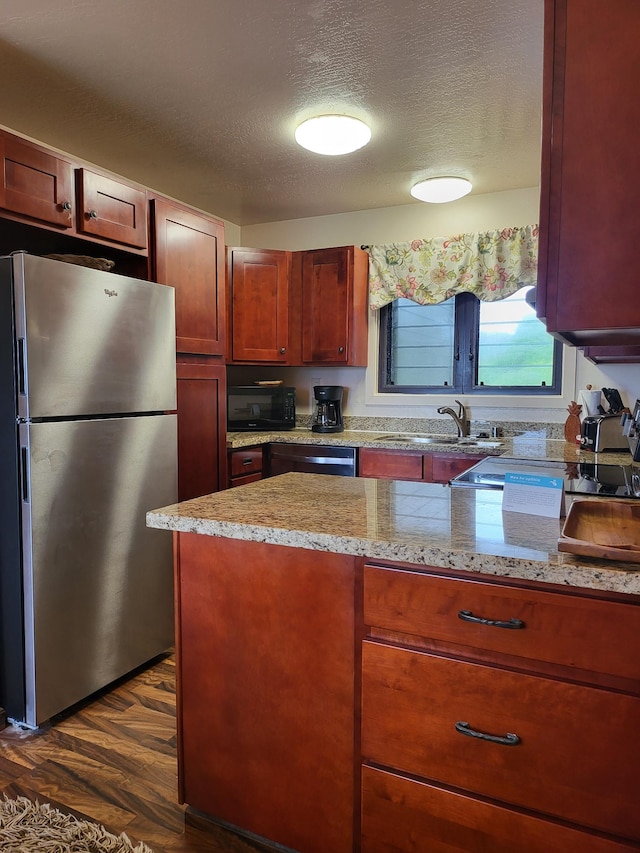 kitchen featuring sink, dark wood-type flooring, stainless steel appliances, light stone counters, and a textured ceiling