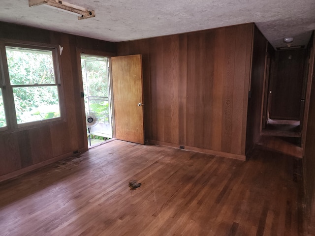 foyer entrance with dark wood-type flooring, a textured ceiling, and wood walls