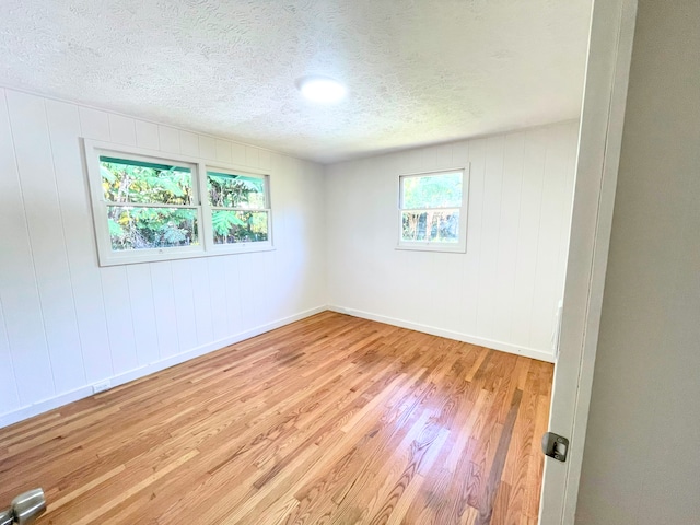 unfurnished room with a textured ceiling and light wood-type flooring