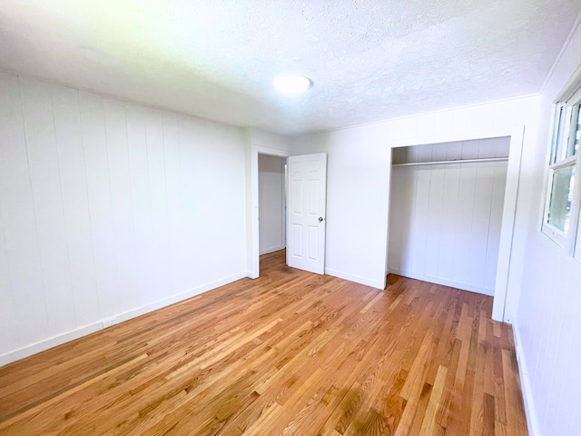 unfurnished bedroom with a closet, light hardwood / wood-style flooring, and a textured ceiling