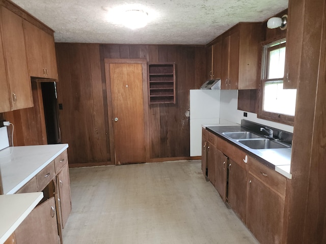 kitchen with sink, a textured ceiling, and wooden walls