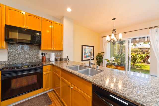 kitchen featuring black appliances, tasteful backsplash, pendant lighting, sink, and light hardwood / wood-style flooring