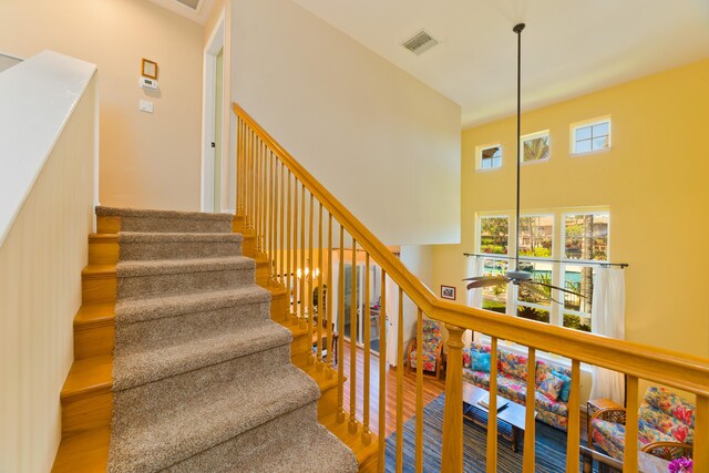 stairs featuring hardwood / wood-style floors and a towering ceiling