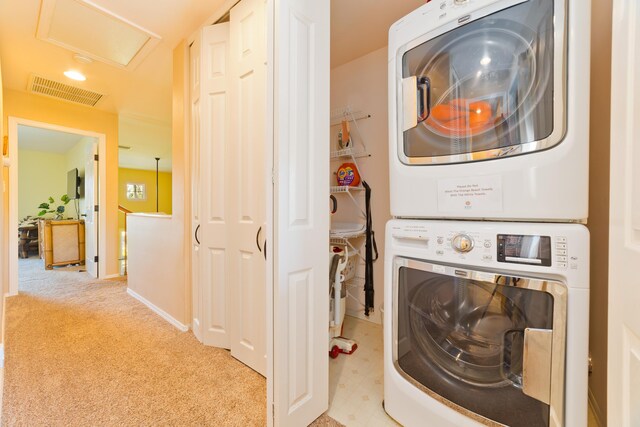 clothes washing area with stacked washer / dryer and light colored carpet