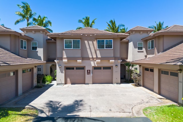 view of front of home with driveway, an attached garage, a tiled roof, and stucco siding