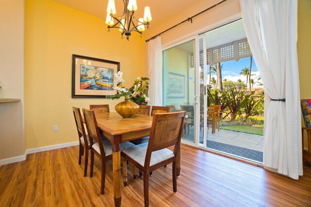 dining space with hardwood / wood-style floors and an inviting chandelier