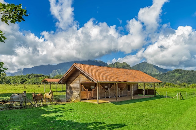 rear view of house featuring a mountain view, a rural view, a patio area, and a lawn