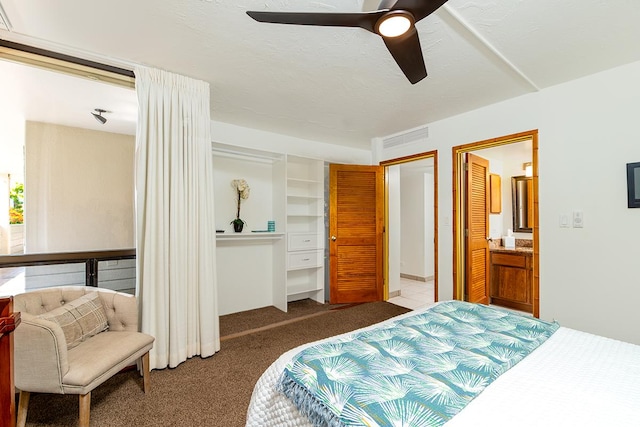 carpeted bedroom with ensuite bath, visible vents, and ceiling fan