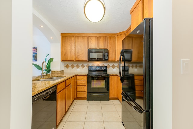 kitchen featuring black appliances, sink, backsplash, light tile patterned floors, and light stone countertops