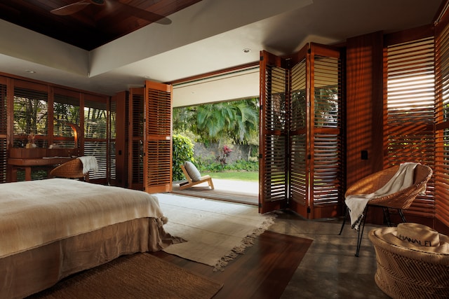 bedroom with a tray ceiling, concrete flooring, and ceiling fan