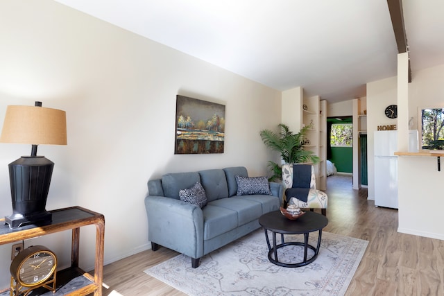 living room with lofted ceiling, light wood-type flooring, and baseboards