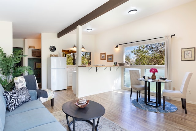 living room with light wood finished floors, beam ceiling, and baseboards