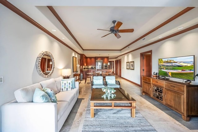 living room featuring a tray ceiling, ceiling fan, and ornamental molding