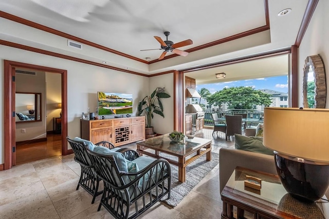 living room featuring ceiling fan, a raised ceiling, and ornamental molding