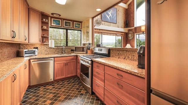 kitchen with light stone countertops, decorative backsplash, stainless steel appliances, and sink