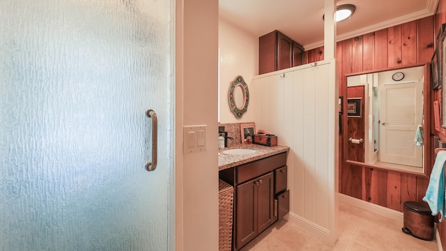 bathroom with tile patterned flooring, a shower, crown molding, wood walls, and vanity