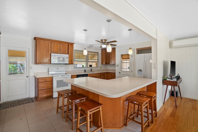 kitchen with a breakfast bar area, white appliances, ceiling fan, light hardwood / wood-style floors, and sink