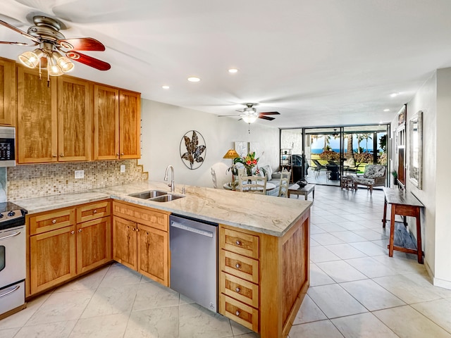 kitchen featuring ceiling fan, sink, kitchen peninsula, backsplash, and appliances with stainless steel finishes