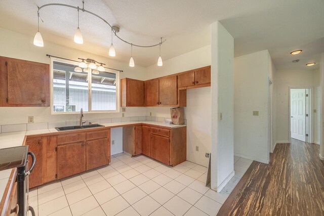 kitchen featuring range, light hardwood / wood-style flooring, rail lighting, pendant lighting, and sink