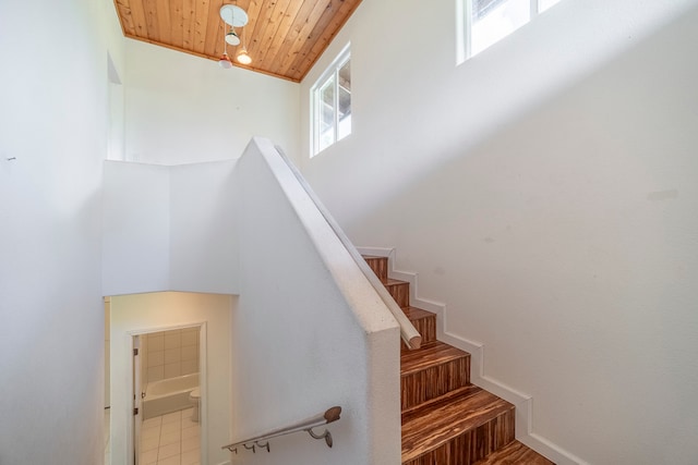 staircase with tile patterned floors, wooden ceiling, and a towering ceiling