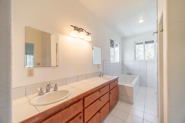 bathroom with dual vanity, tile patterned flooring, and tiled bath