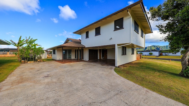 rear view of property with a carport and a yard