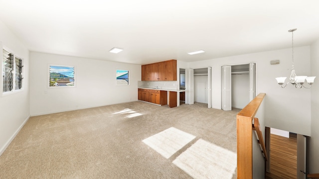 unfurnished living room with light colored carpet and a chandelier