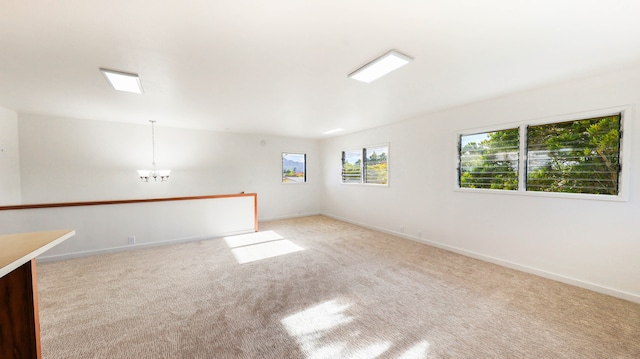 carpeted spare room featuring a notable chandelier