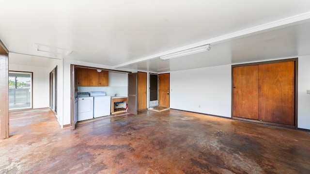 unfurnished living room featuring concrete floors and washing machine and clothes dryer