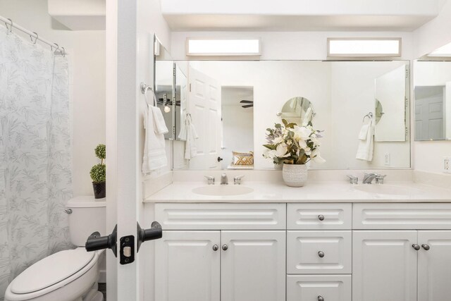 bathroom featuring dual vanity and toilet