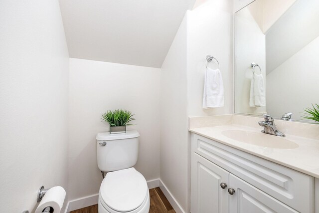 bathroom featuring vaulted ceiling, vanity, wood-type flooring, and toilet