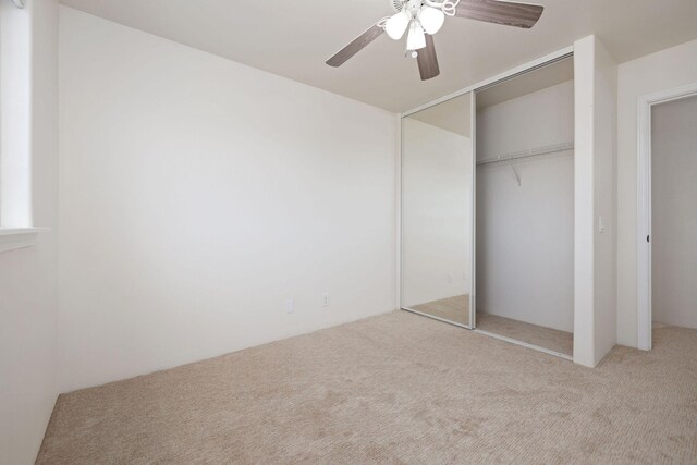 unfurnished bedroom with light carpet, a closet, and ceiling fan