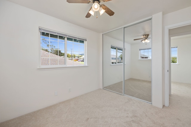 unfurnished bedroom with ceiling fan, a closet, and light colored carpet