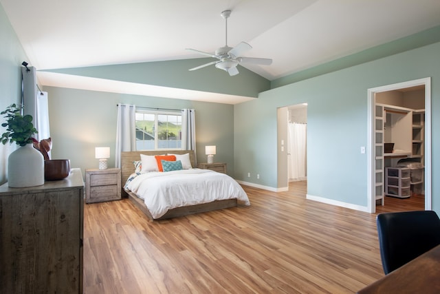 bedroom featuring vaulted ceiling, a walk in closet, ceiling fan, and light hardwood / wood-style flooring