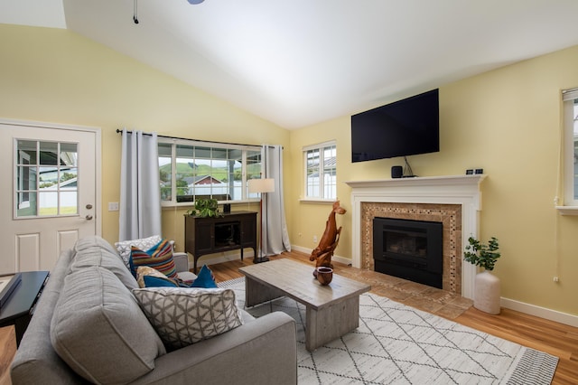 living room with lofted ceiling, a fireplace, and light wood-type flooring