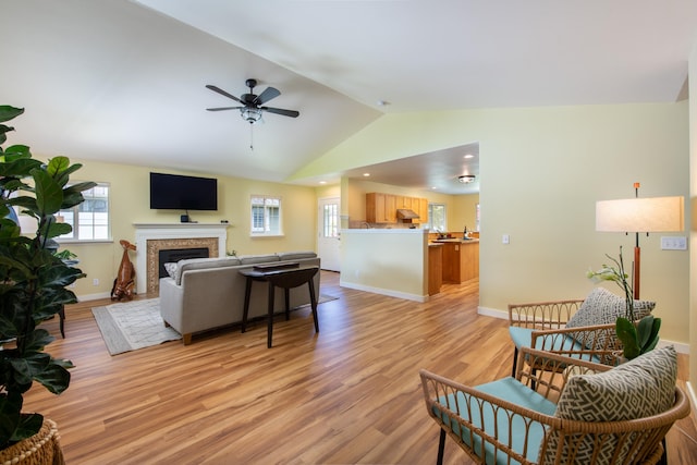 living room featuring ceiling fan, vaulted ceiling, and light wood-type flooring