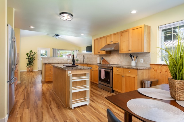 kitchen with light stone counters, backsplash, stainless steel appliances, and a center island