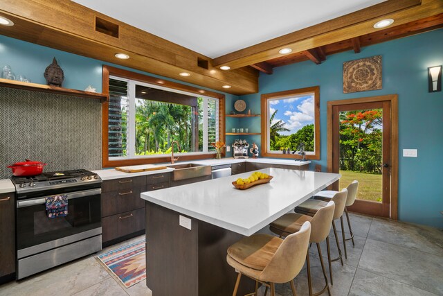 kitchen featuring stainless steel appliances, decorative backsplash, sink, beam ceiling, and light tile patterned floors