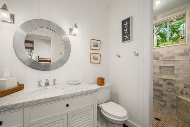 bathroom featuring vanity, toilet, and a tile shower