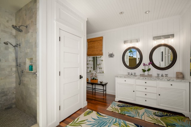 bathroom featuring a tile shower, vanity, and wood-type flooring