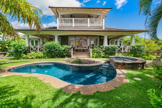 back of house featuring a balcony, ceiling fan, a pool with hot tub, and a lawn