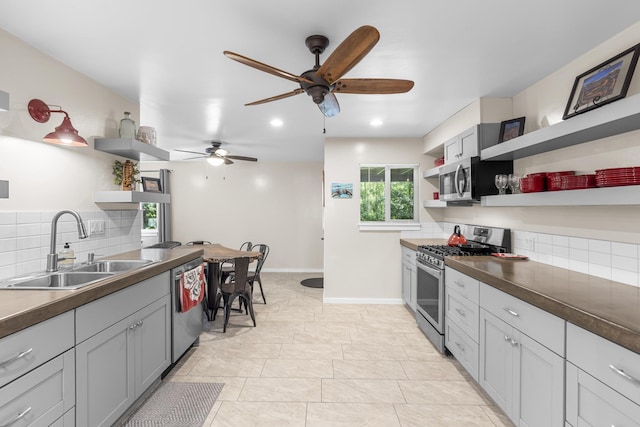 kitchen with sink, gray cabinetry, appliances with stainless steel finishes, ceiling fan, and decorative backsplash