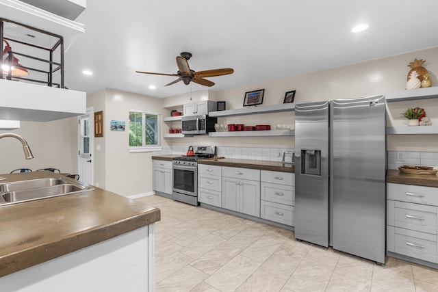 kitchen featuring gray cabinets, sink, backsplash, ceiling fan, and stainless steel appliances