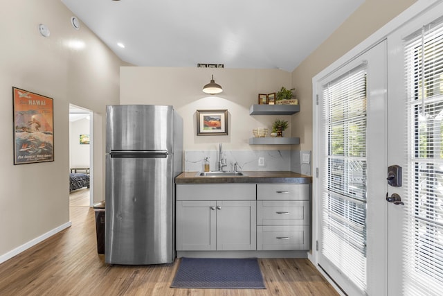 kitchen with sink, pendant lighting, gray cabinetry, stainless steel fridge, and hardwood / wood-style flooring