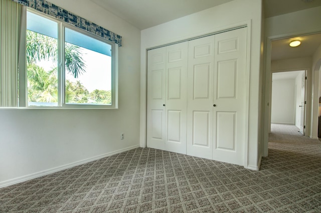 unfurnished bedroom featuring a closet and dark carpet