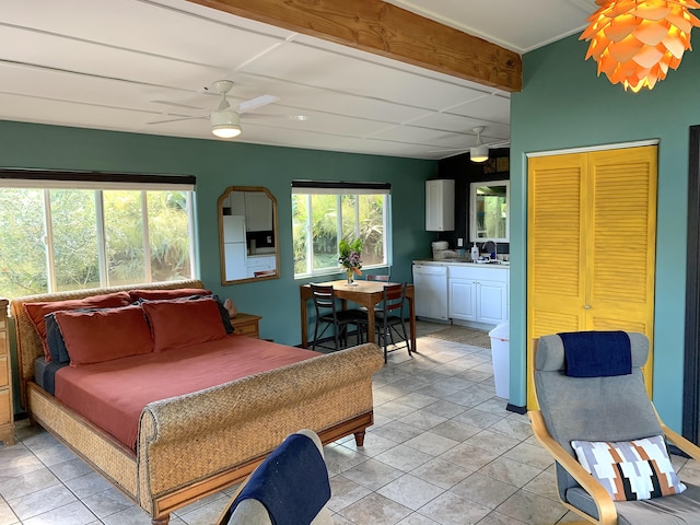 tiled bedroom featuring sink, ceiling fan, beam ceiling, white refrigerator, and connected bathroom