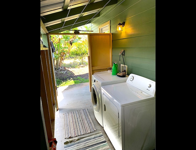 clothes washing area featuring wooden walls and washer and clothes dryer