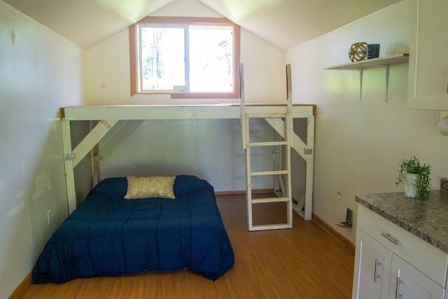 bedroom featuring light wood-type flooring and vaulted ceiling